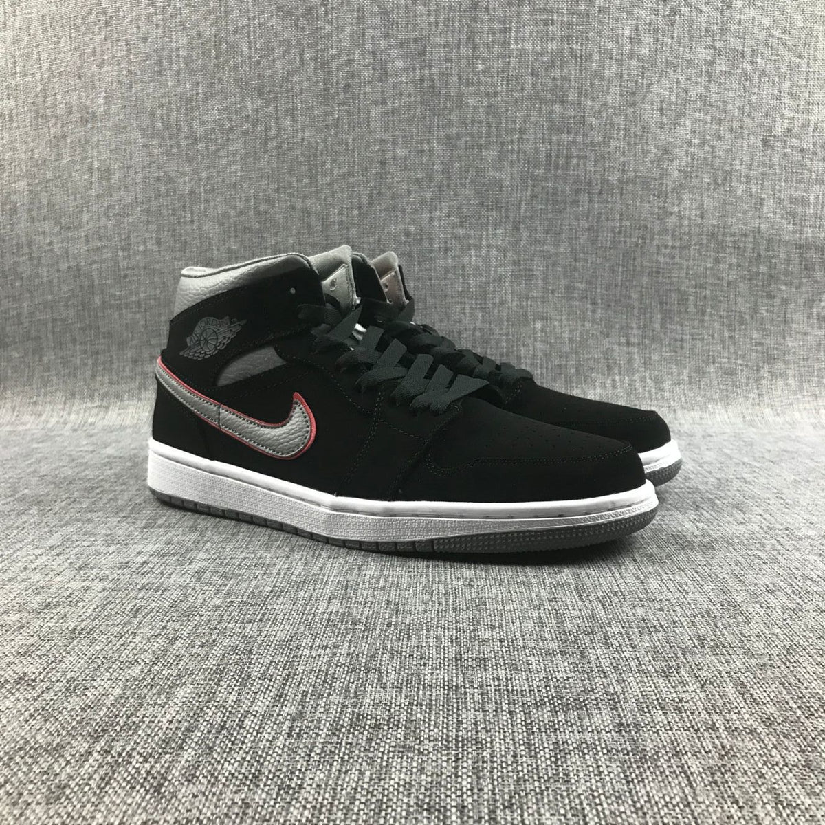 Pair of black and grey Air Jordan 1 Mid sneakers shown from a front three-quarter angle.
