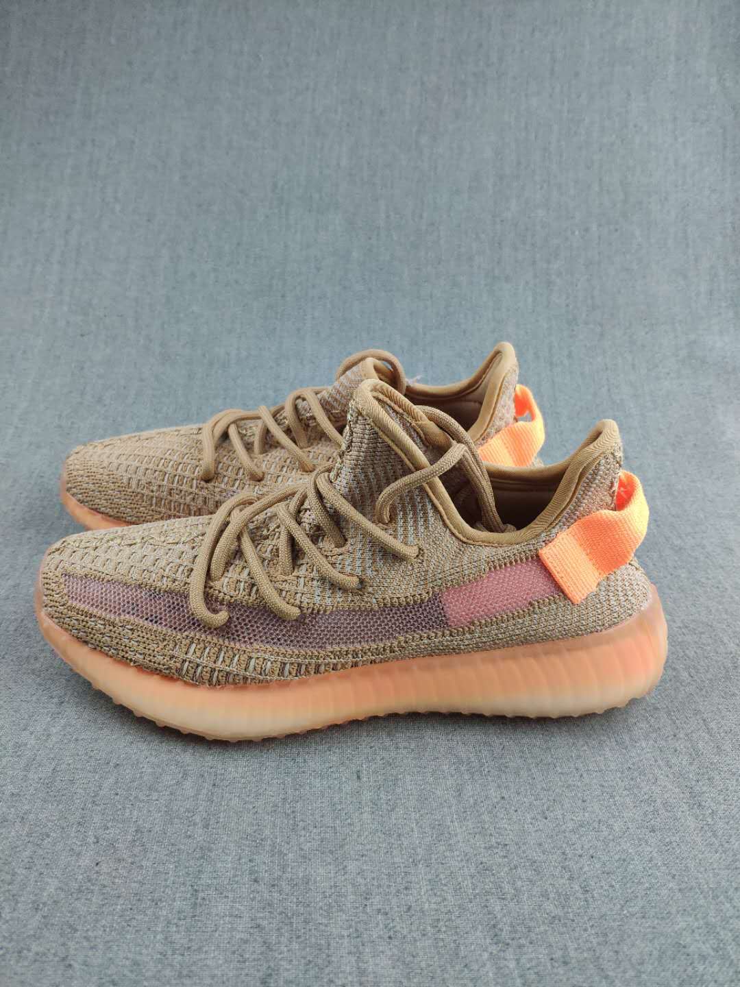 Side view of tan low-top sneakers with tonal laces, a mauve stripe, orange heel details, and textured uppers.