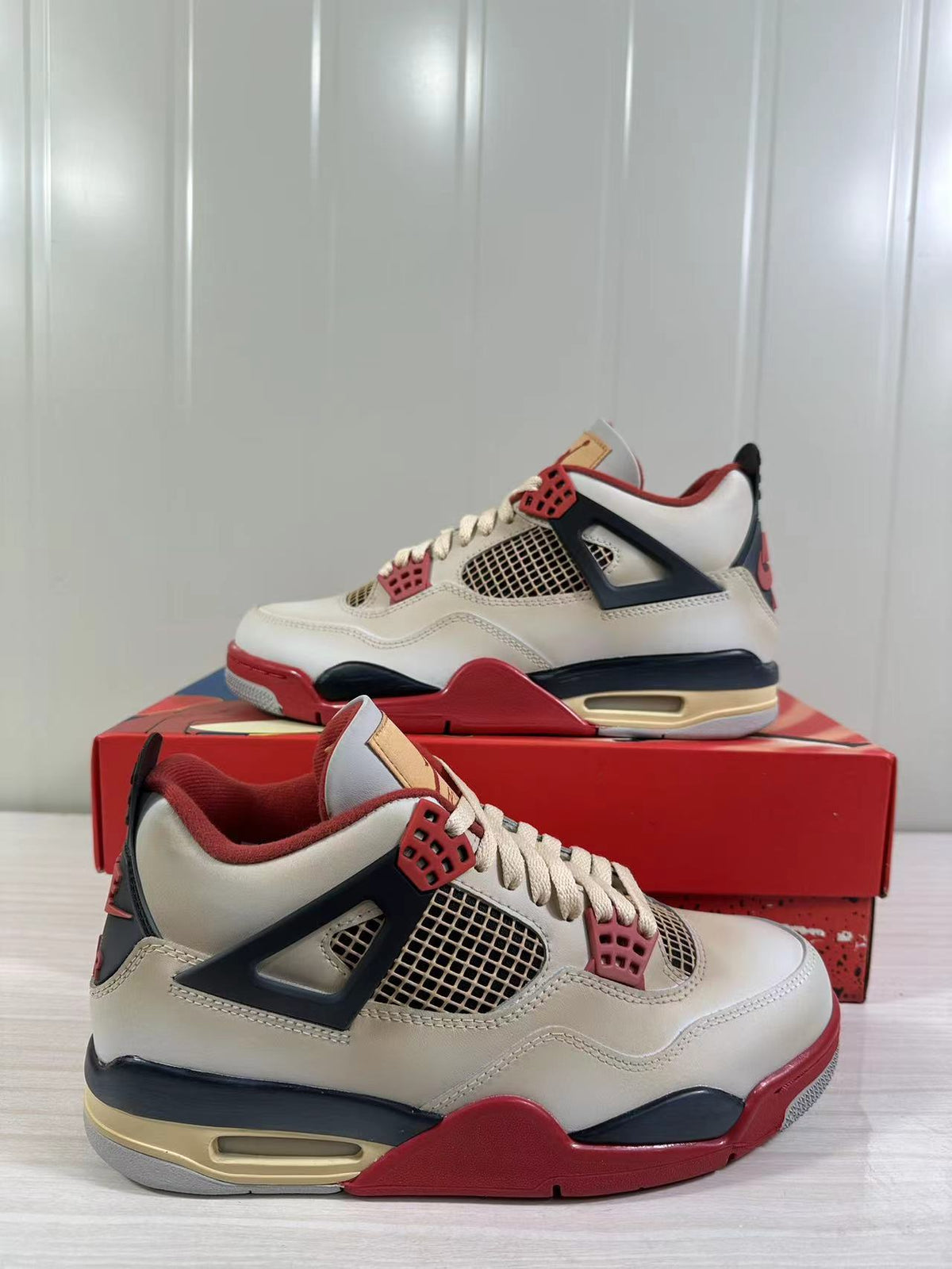 Close angled view of the sneakers showing the off-white upper, red accents, mesh panels, and cushioned midsole.