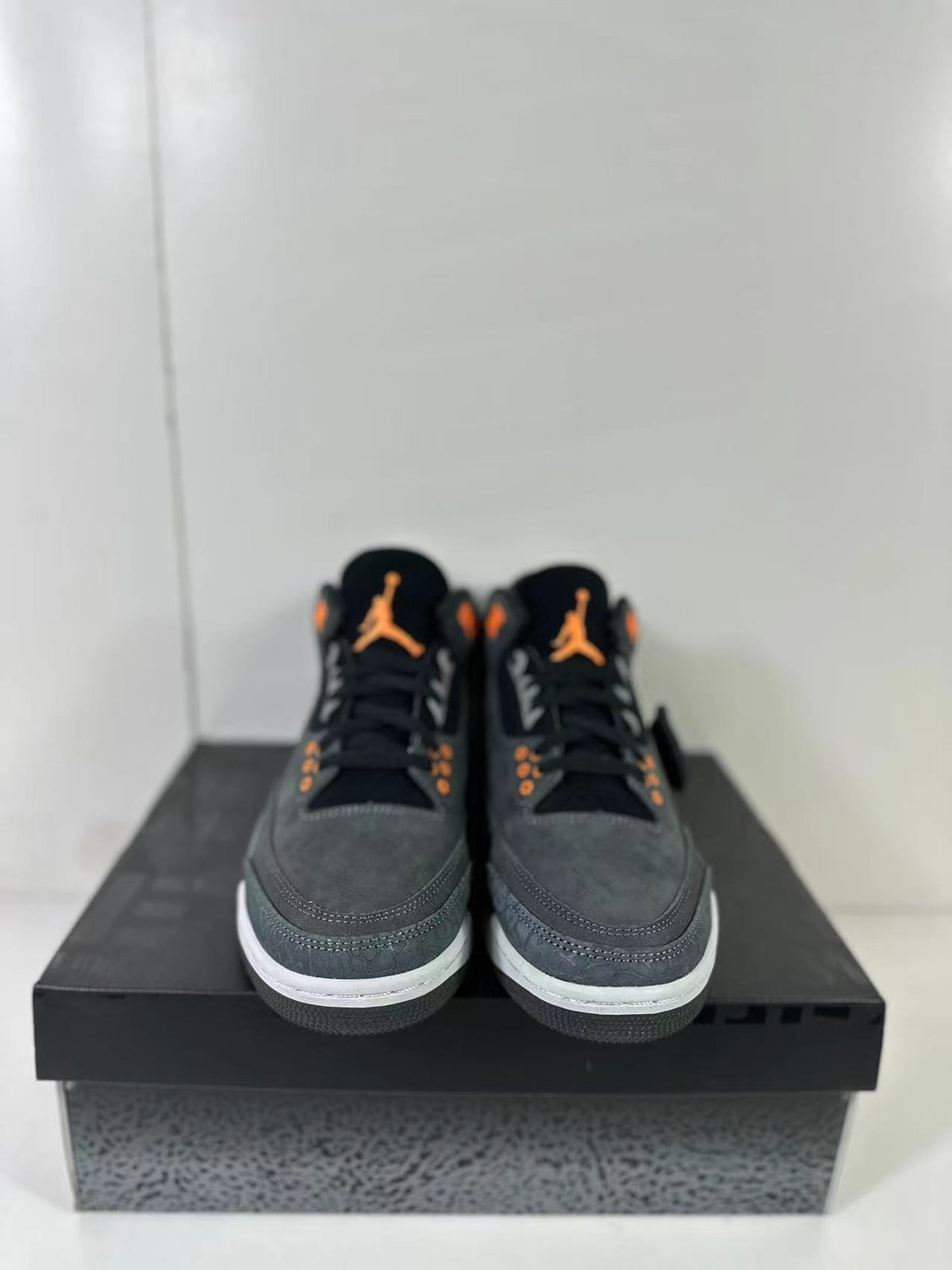 Front view of the pair showing black tongues, orange branding and eyelets, gray uppers, and white toe-area midsoles.