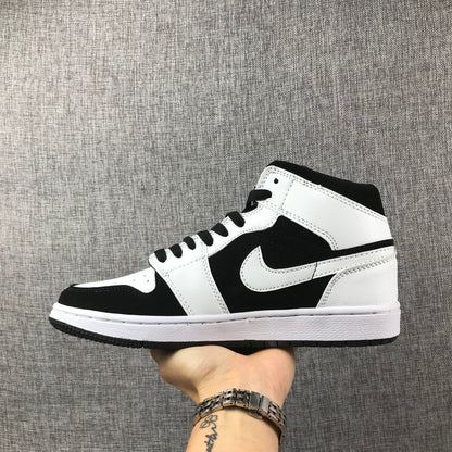 Side profile of a black-and-white Jordan Air Jordan 1 Mid sneaker held against a gray background.