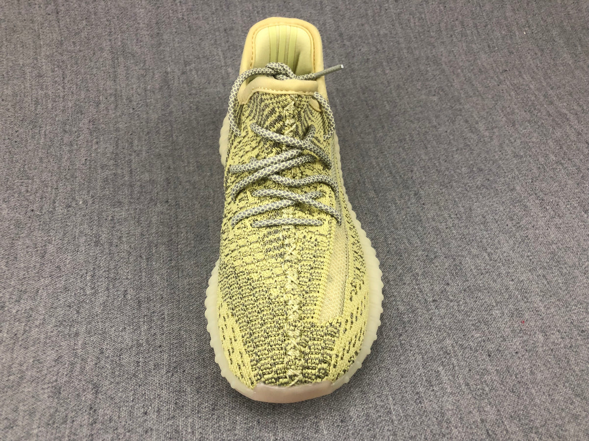 Top view of an olive-yellow and black knit-style sneaker with contrasting round laces.