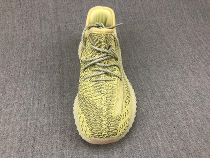 Top view of an olive-yellow and black knit-style sneaker with contrasting round laces.