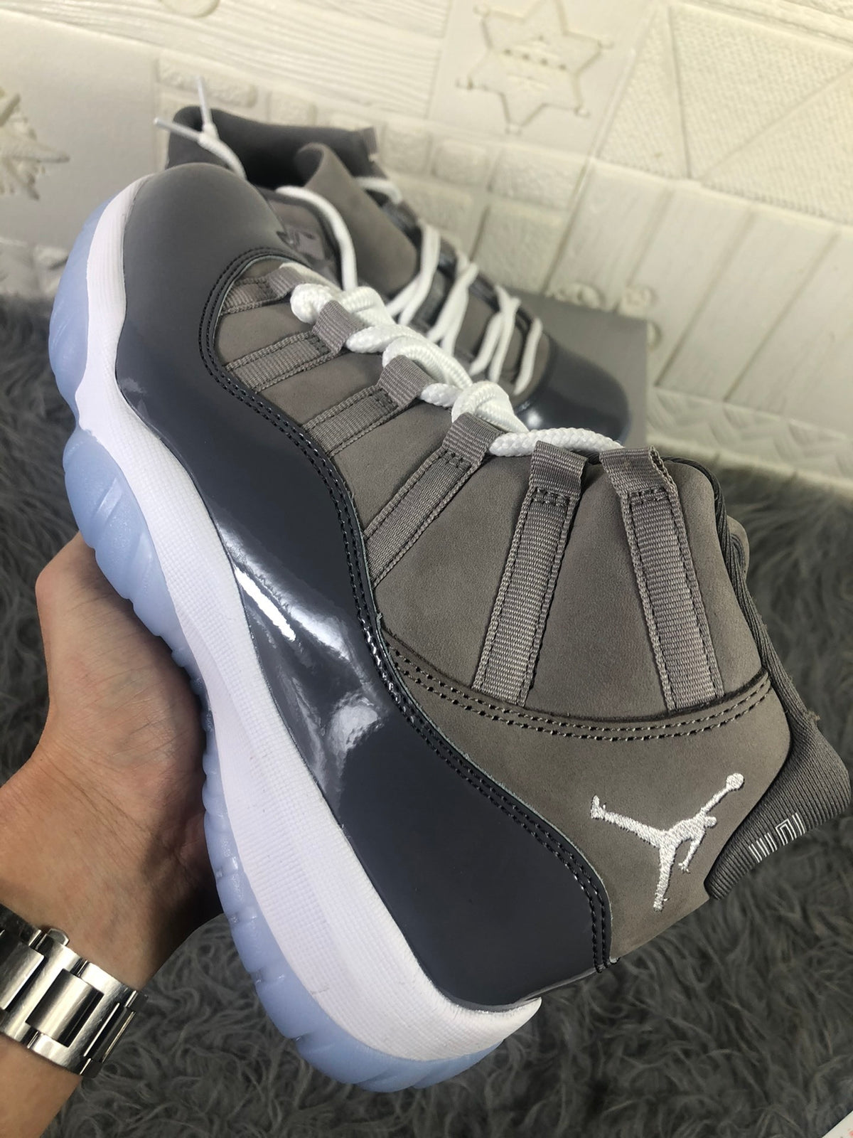 Angled close-up of the lacing system, grey upper panels, glossy overlay, and Jordan tongue branding.