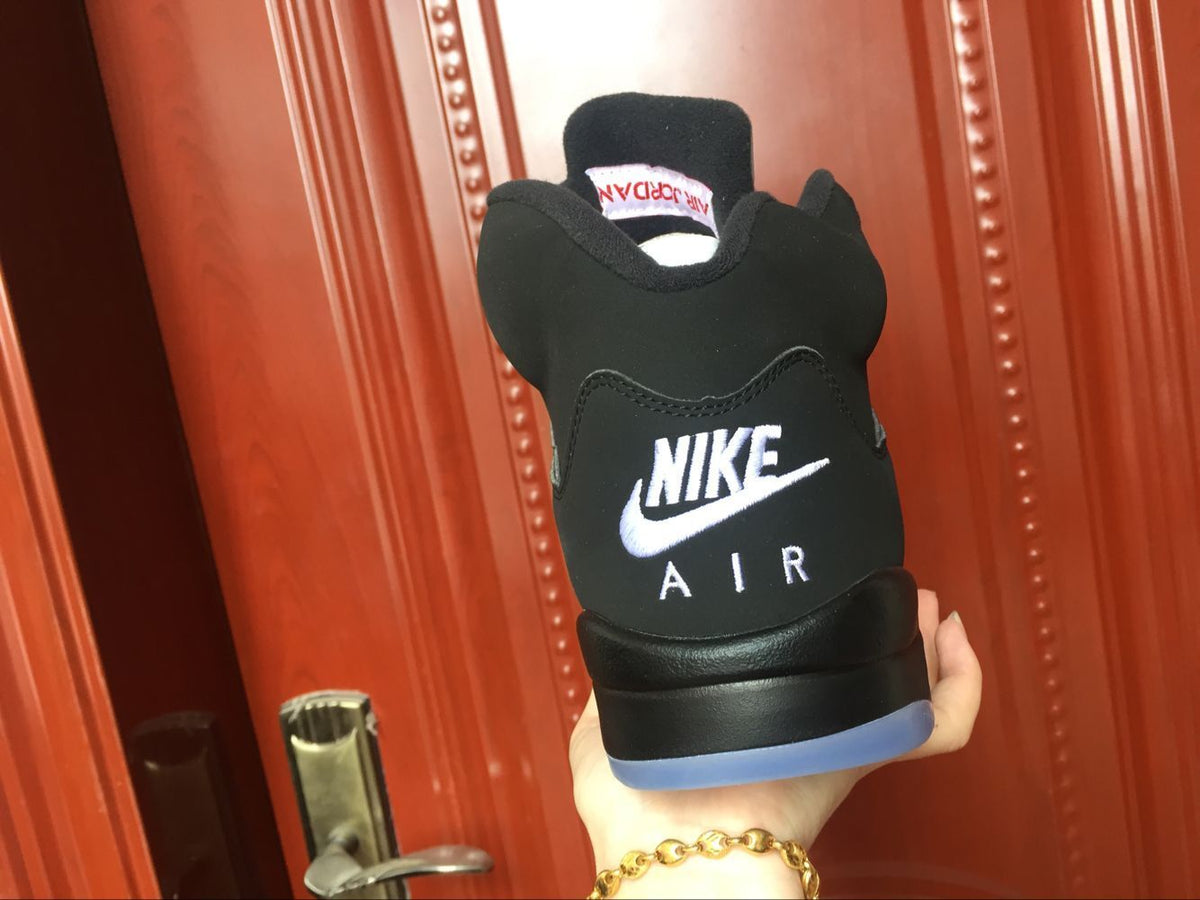 Rear view of a black sneaker showing white Nike Air branding and a translucent blue heel outsole.
