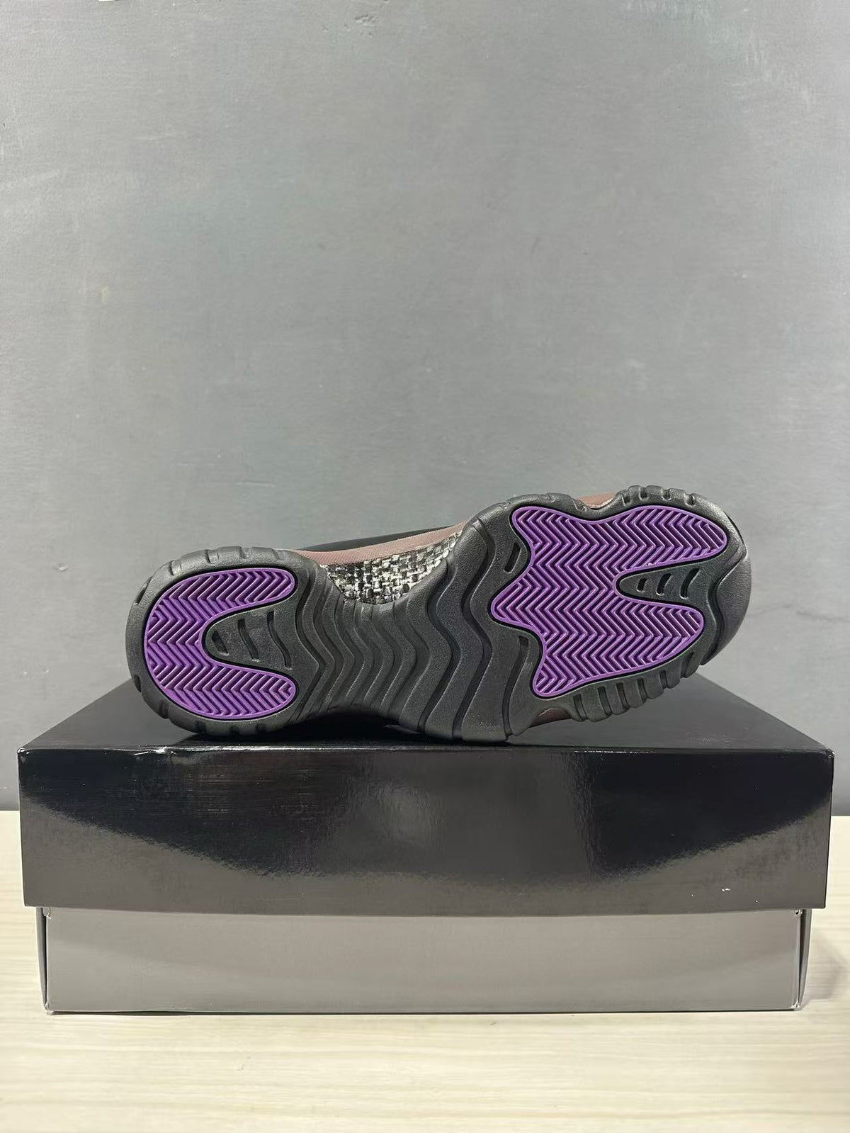Bottom view of the sneaker showing the dark outsole and purple traction areas.