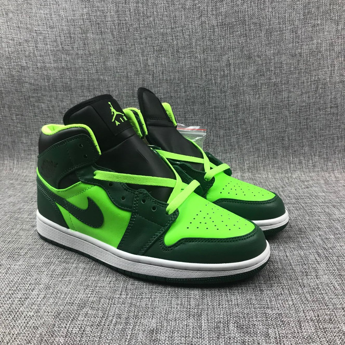Pair of dark green and fluorescent green Jordan 1 Mid sneakers shown from a front three-quarter angle.