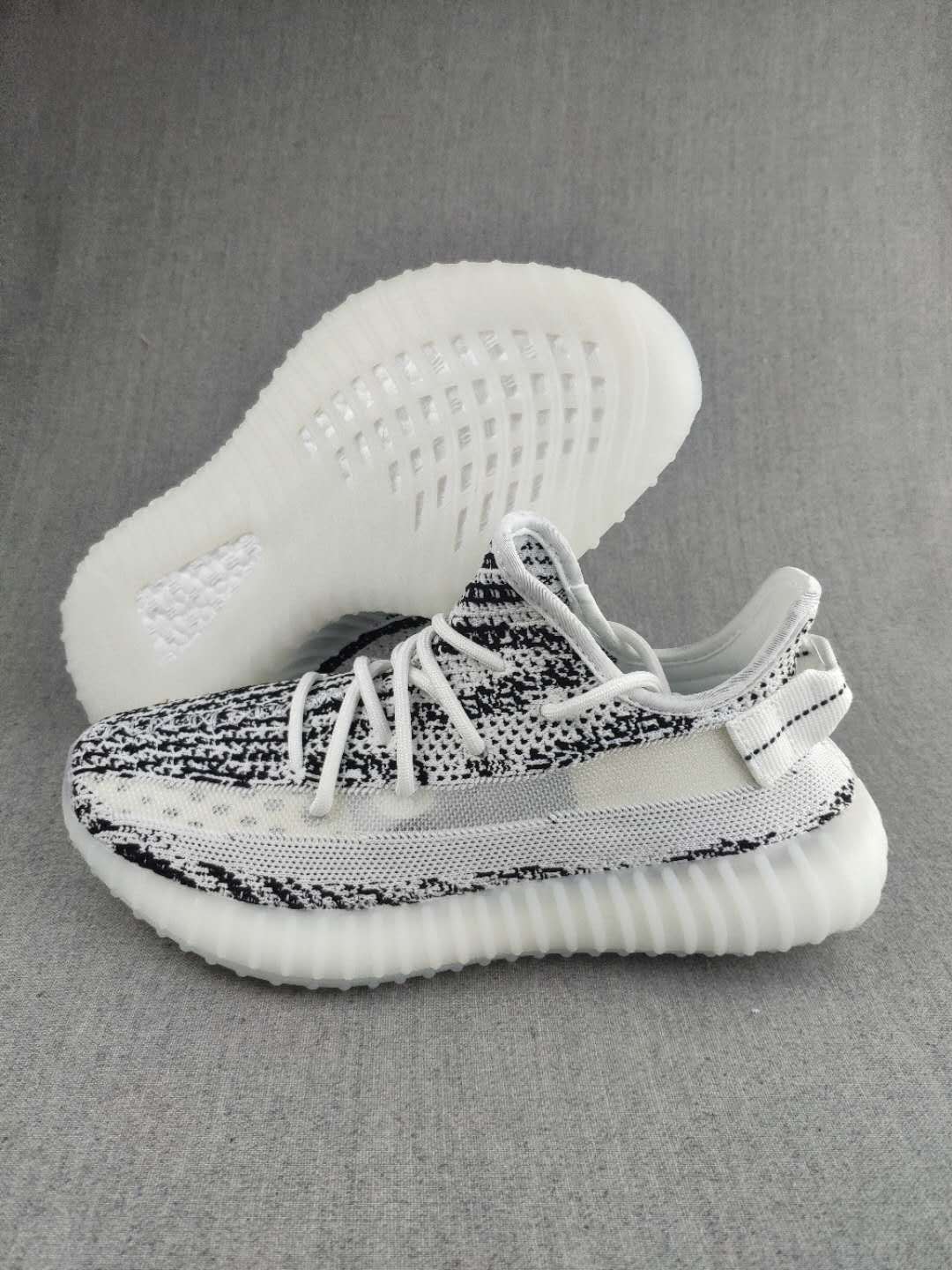 Side view of a black-and-white knit sneaker with the translucent sole visible underneath.
