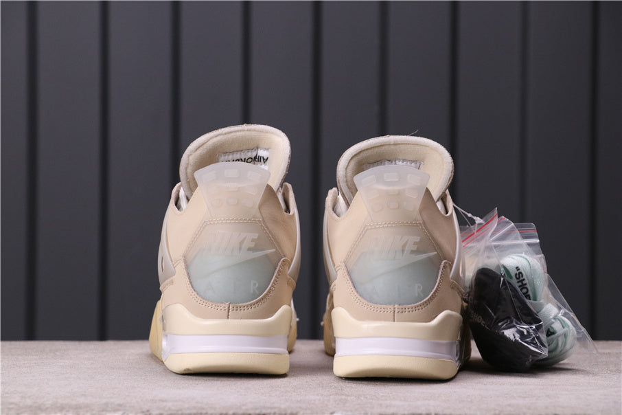 Rear view of a pair of cream and off-white Jordan 4 style sneakers with translucent heel details and additional laces in packaging.