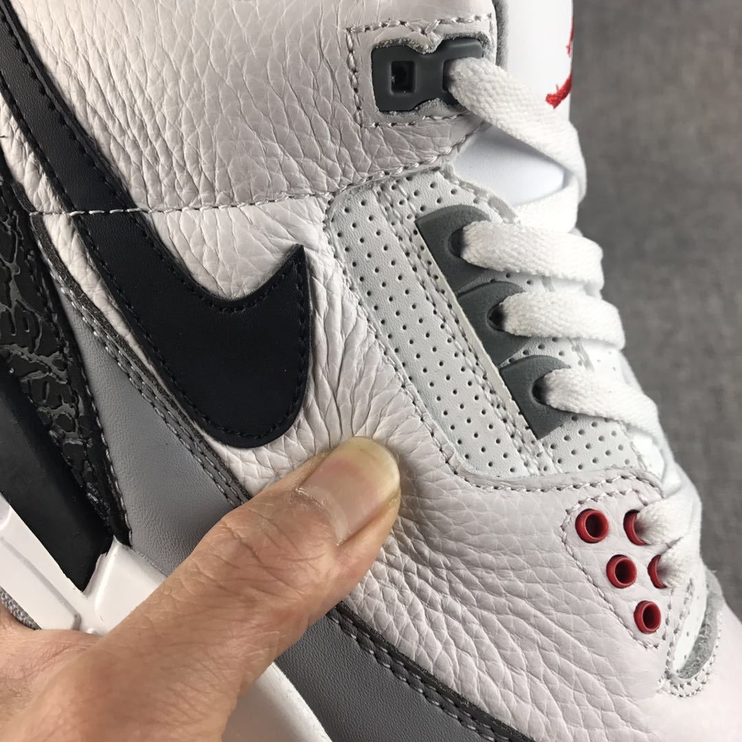 Close-up of the textured white upper, black Swoosh, perforated eyestay, and red lace eyelets.