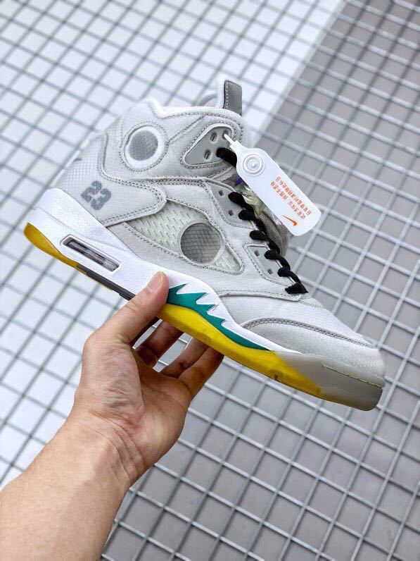 Side profile of the sneaker showing grey overlays, circular translucent panel, black laces, and yellow-teal accents.