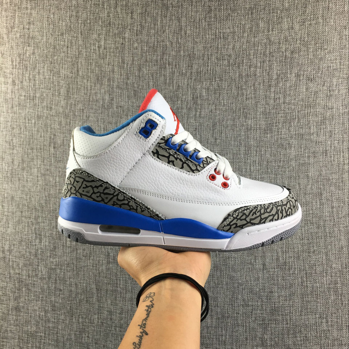 Air Jordan 3 Retro sneaker in white, blue, red, and gray, shown in side profile above its box with a visible size label.