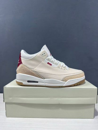 Side profile of a cream and red Air Jordan 3 Retro sneaker displayed on its box.