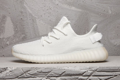 Side profile of a white Yeezy 350 V2 sneaker with a translucent ribbed sole.