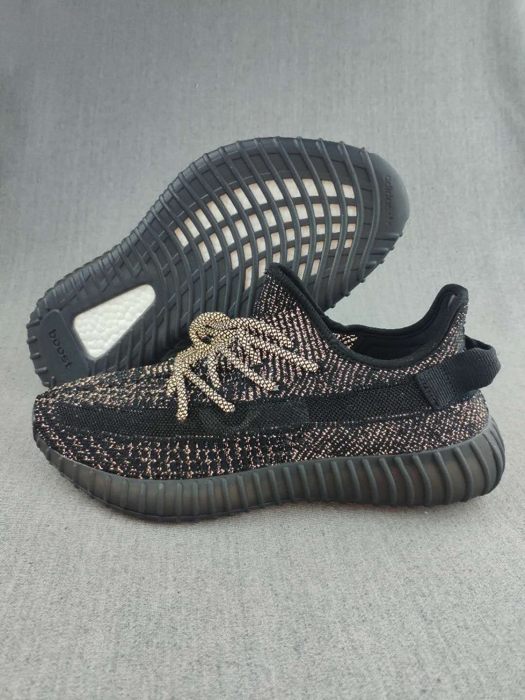 Pair of black Yeezy 350 V2-style sneakers showing the patterned knit upper, matching laces, and ribbed outsole.