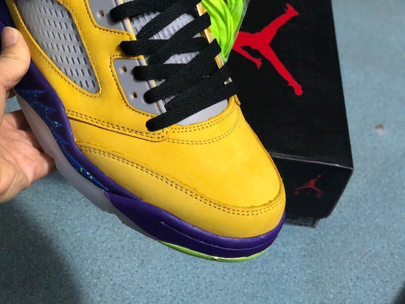 Close-up of the yellow sneaker toe box, black laces, mesh panel, and layered purple outsole.