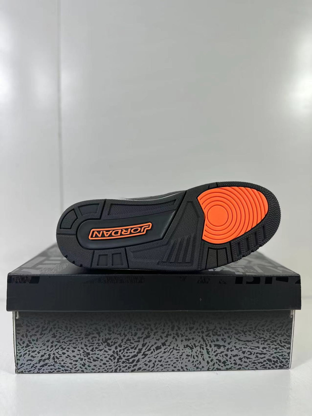 Close-up of the outsole showing concentric orange traction detailing, black tread sections, and the Jordan wordmark.