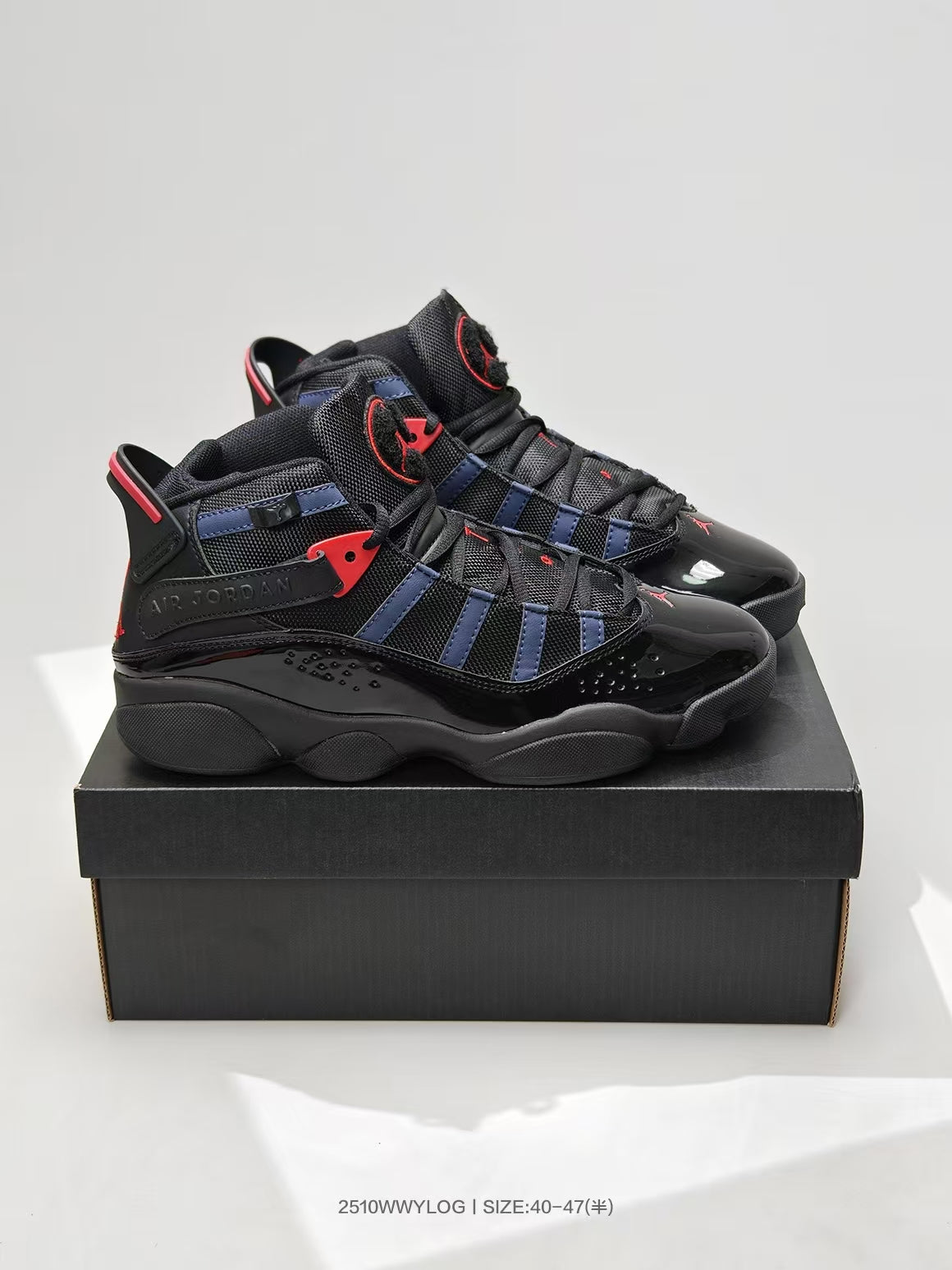 Pair of black, navy, and red high-top sneakers displayed on a black shoebox.
