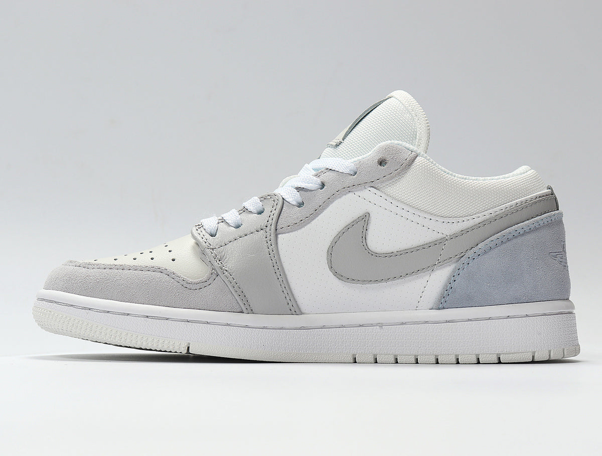 Side profile of a white and light grey low-top Jordan sneaker with a perforated toe box, layered panels, Swoosh detail and rubber outsole.