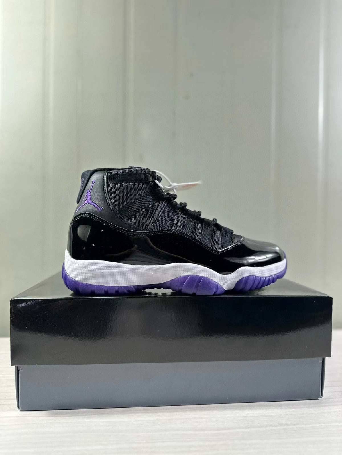 Side profile showing the glossy black upper, white midsole, purple outsole, and high-top collar.