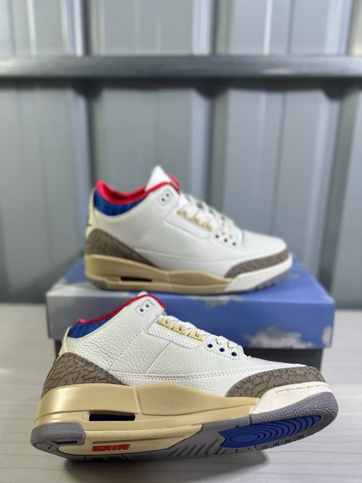 Angled view showing the white upper, patterned overlays, blue outsole detail, and sculpted midsole.