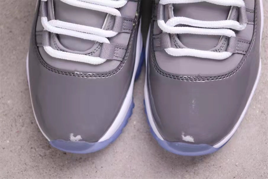 Close-up of the grey patent-style toe sections, white laces, and translucent blue outsole edges.
