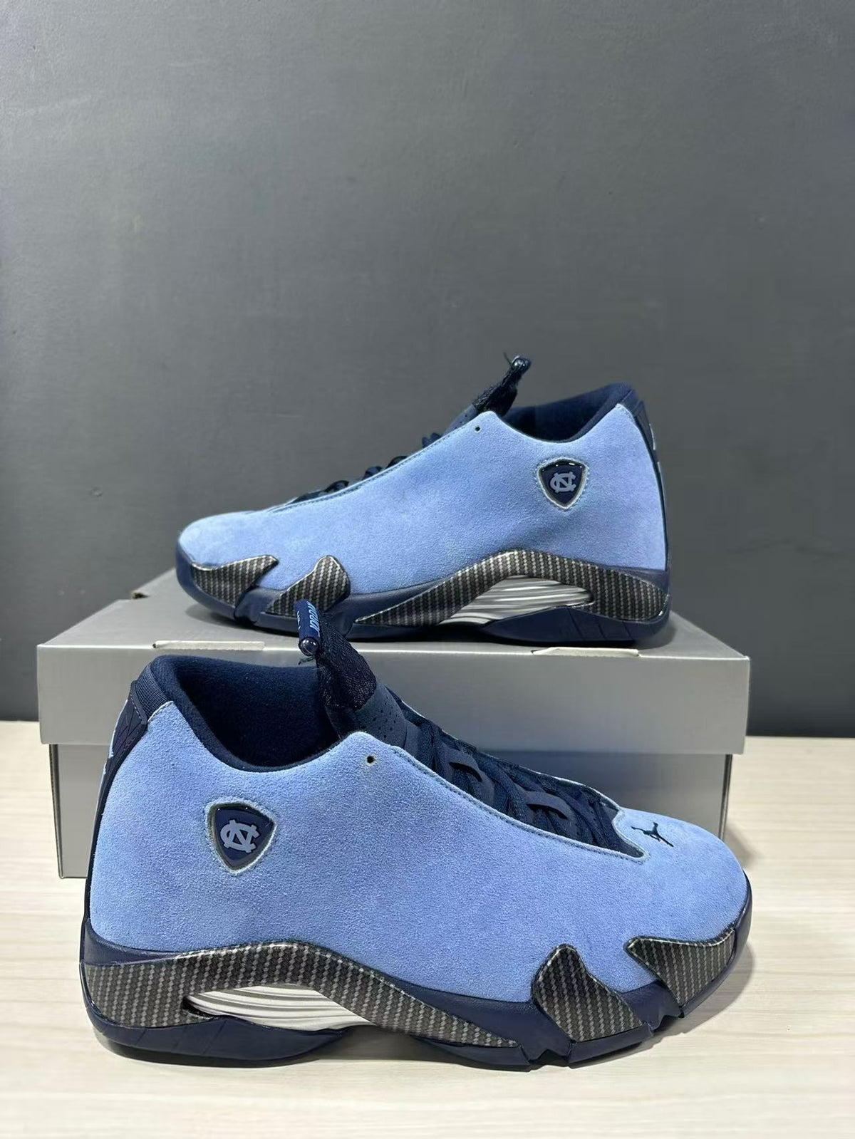 Pair of blue Jordan Air Jordan 14 sneakers shown from angled side views with navy collars and textured overlays.