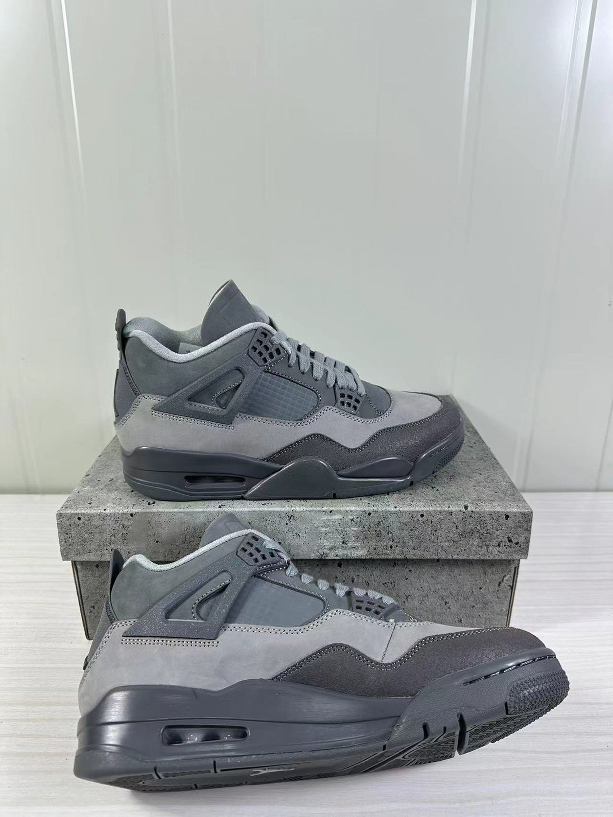 Angled side view of the pair highlighting the layered grey panels, mesh sections, and dark rubber soles.