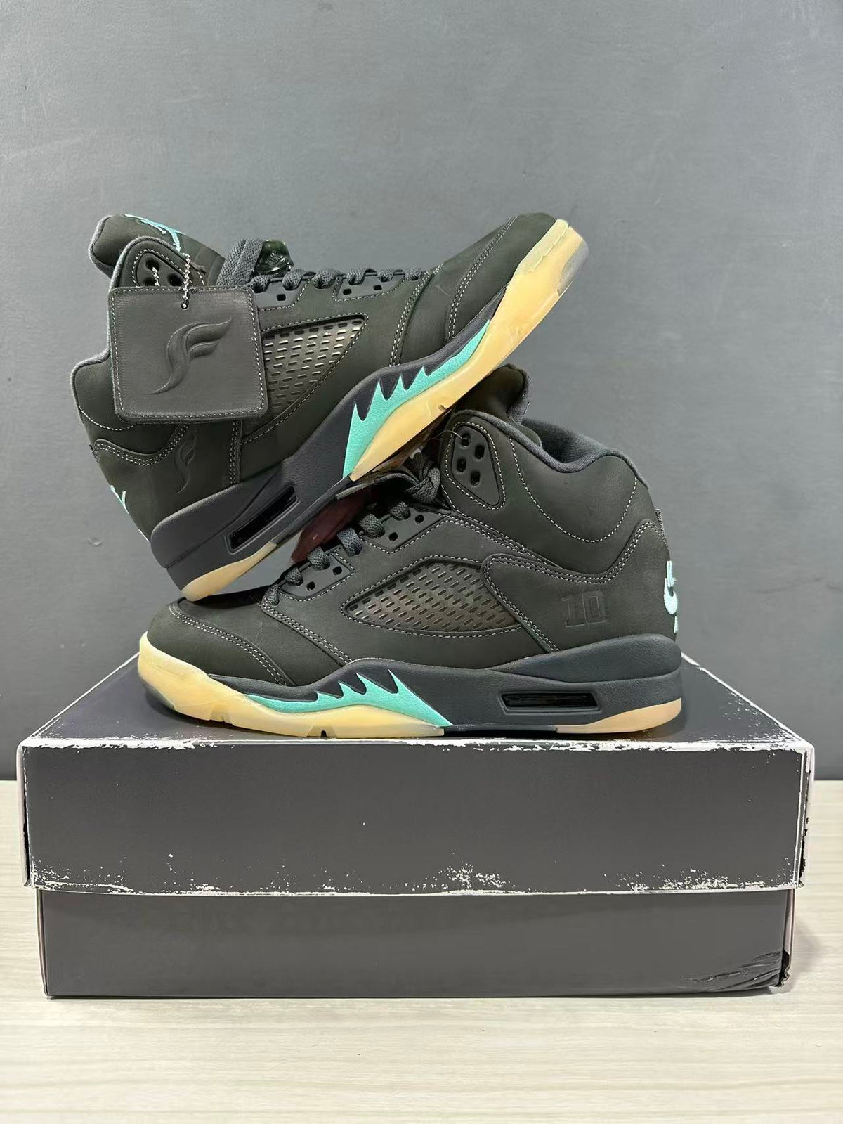 Pair of dark green and black Jordan Air Jordan 5 sneakers arranged on a shoe box, showing both outer sides.