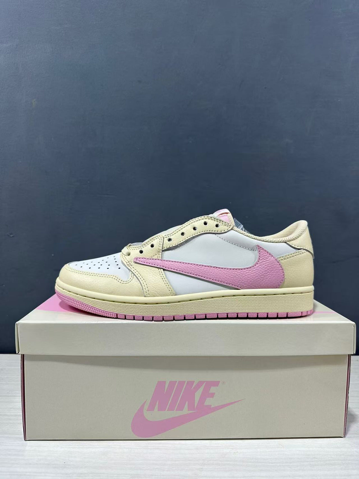 Side profile of the low-top sneaker showing the cream overlays, white panels and pink Swoosh.