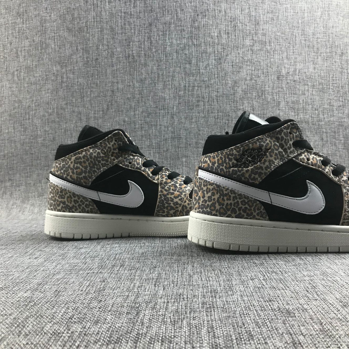 Pair of leopard-print and black mid-top sneakers shown from the side.