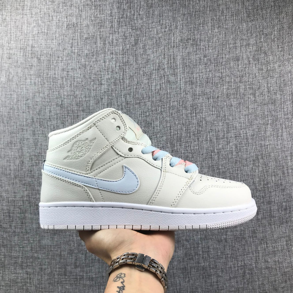 Side profile of an off-white high-top Jordan sneaker with a pastel blue Swoosh and blue-and-pink laces.