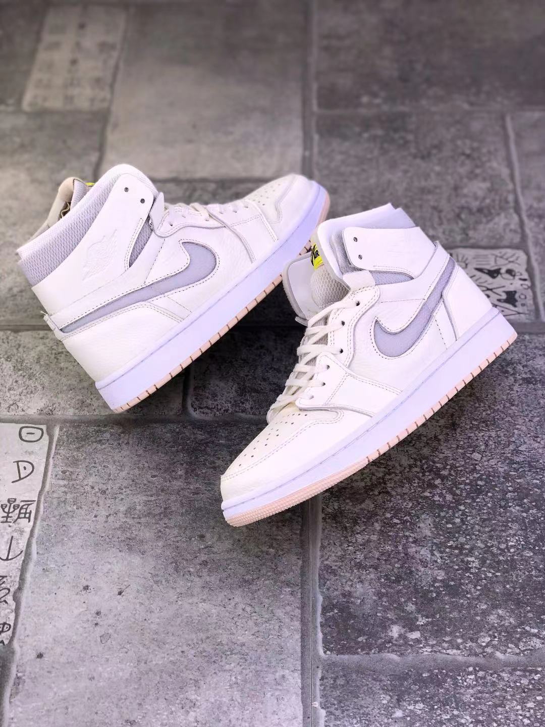 Pair of pearl white high-top sneakers arranged on a tiled surface, showing both outer sides and pale pink outsoles.