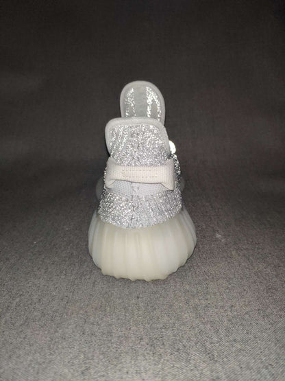 Front view of a silver-gray sneaker showing the rounded toe, knit upper, laces, and padded tongue.
