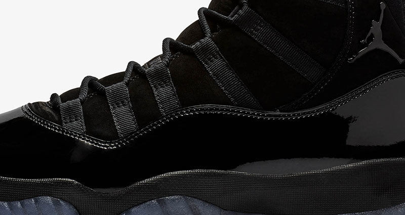 Close-up studio view of the black laces, glossy side panel, and midsole.