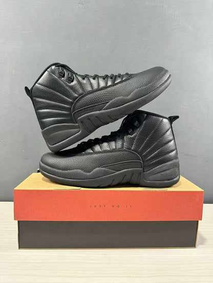 Black Jordan high-top sneakers displayed in opposite side profiles on a shoebox.