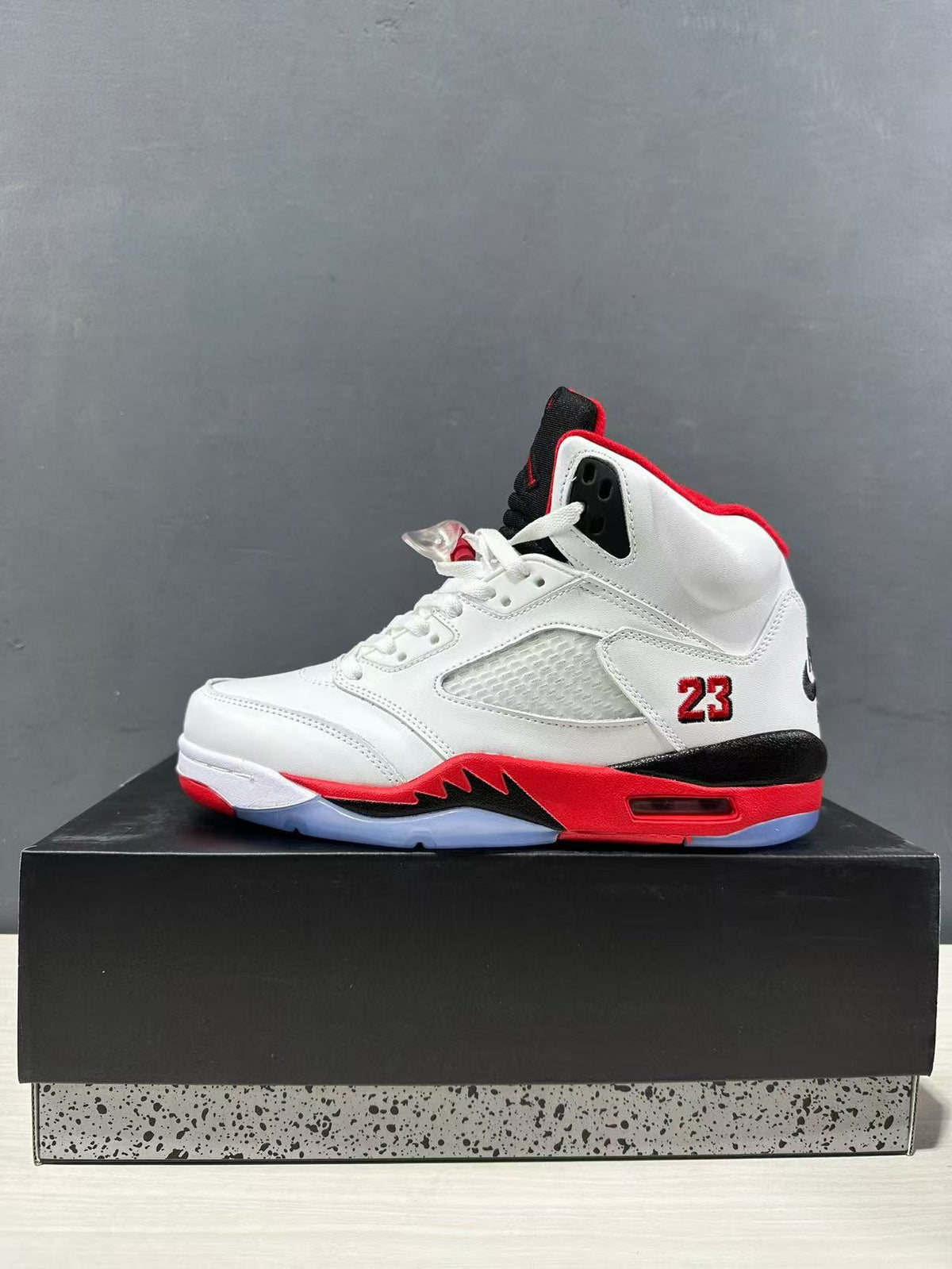 Side profile of a white high-top sneaker with red collar lining, black heel accent, mesh side panel, and visible number 23.