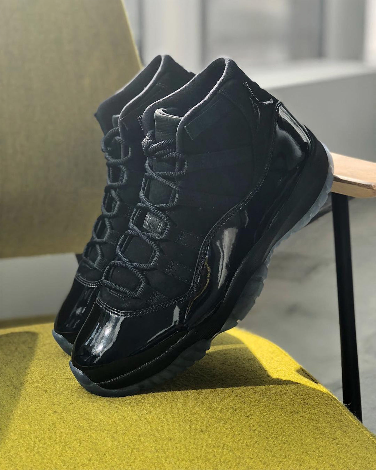 Black high-top sneakers photographed indoors on a chair and tabletop.