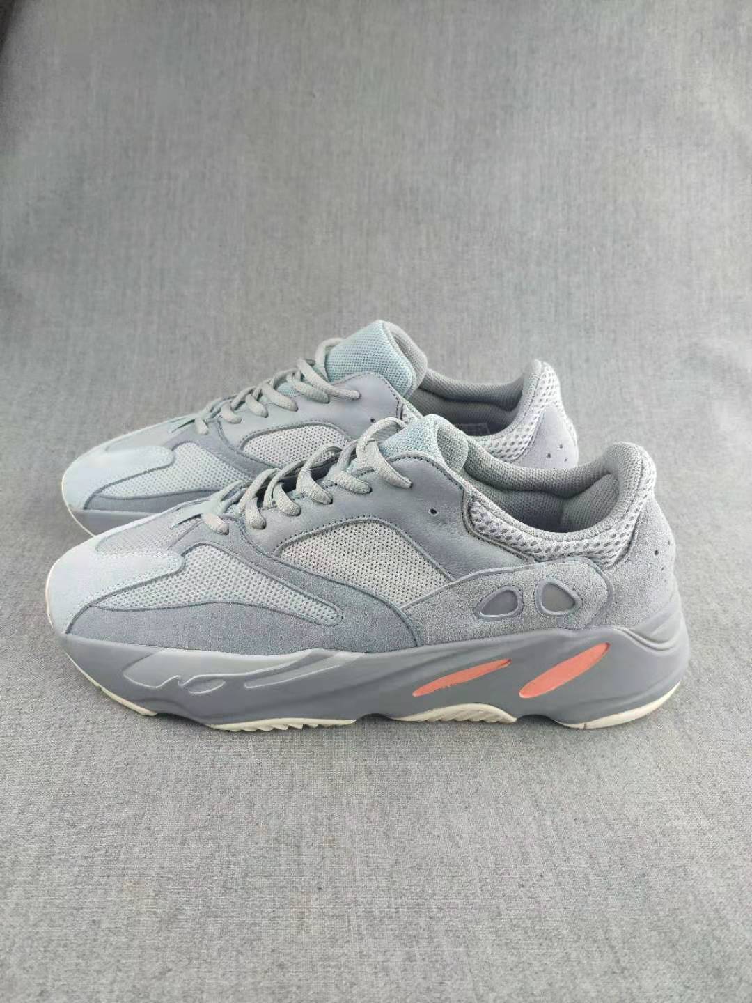 Pair of gray lace-up sneakers shown from the side, with mesh panels and coral accents on the soles.