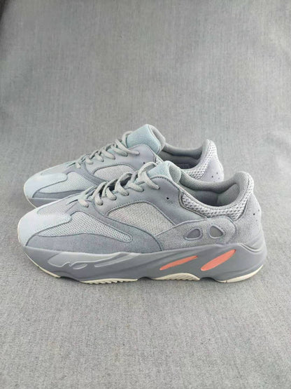 Pair of gray lace-up sneakers shown from the side, with mesh panels and coral accents on the soles.