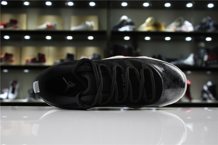 Top-down view of one sneaker showing black laces, padded collar, and a dark upper with a silver toe section.