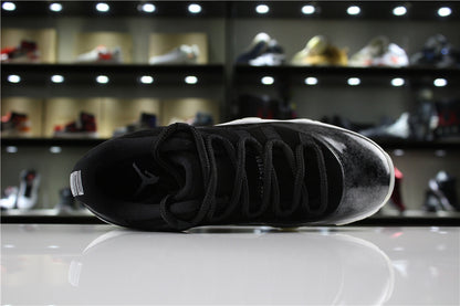 Top-down view of one sneaker showing black laces, padded collar, and a dark upper with a silver toe section.