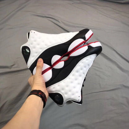 Two sneakers held together to show their side profiles, black midsoles, white panels, and red outsole edges.