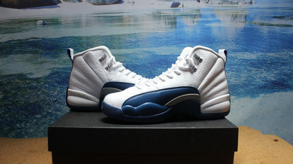 Three-quarter view of the white and navy high-top pair on a black platform.