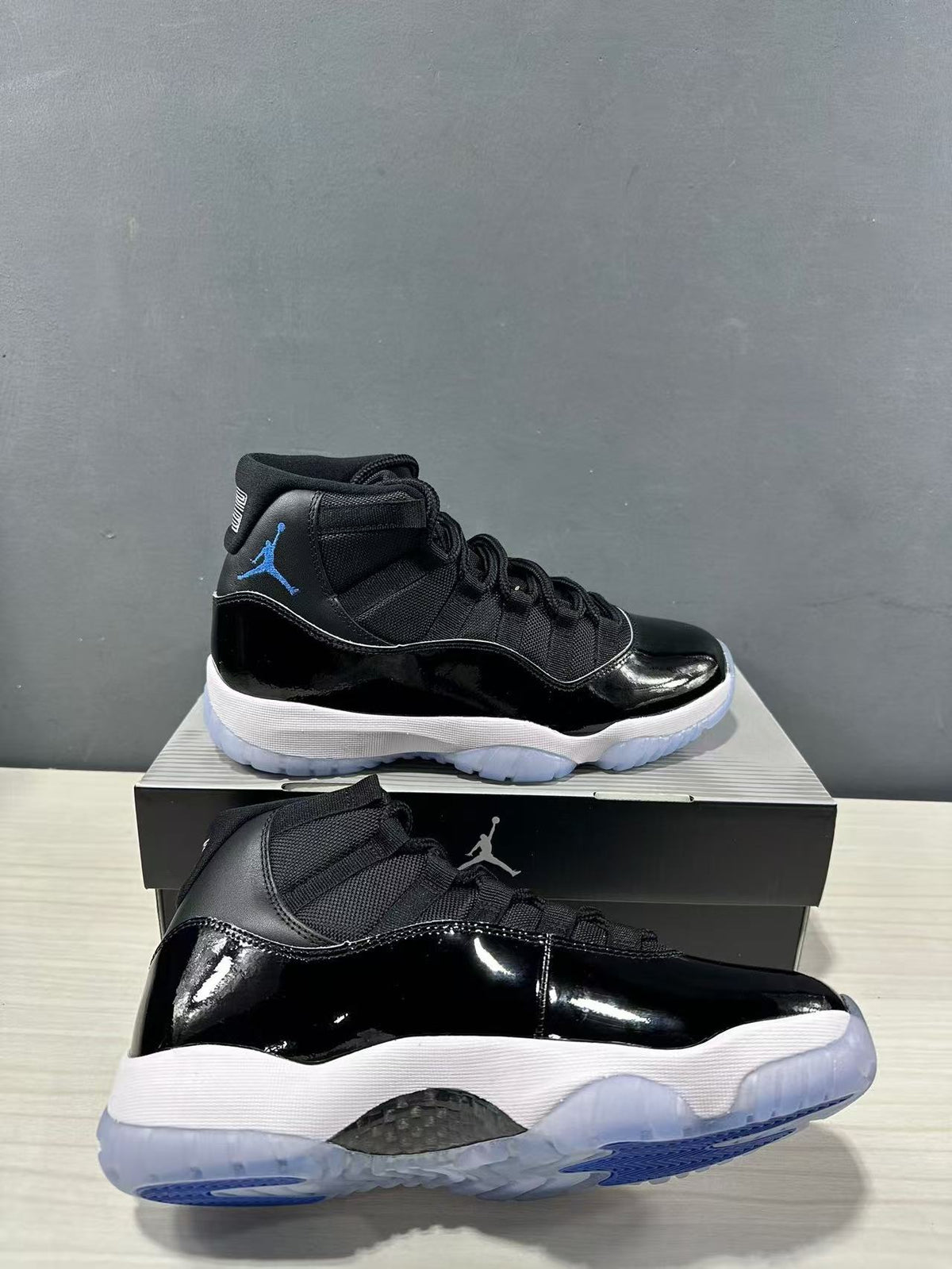 Angled view of two black and blue high-top sneakers showing the glossy black panels, white midsoles, and translucent outsoles.