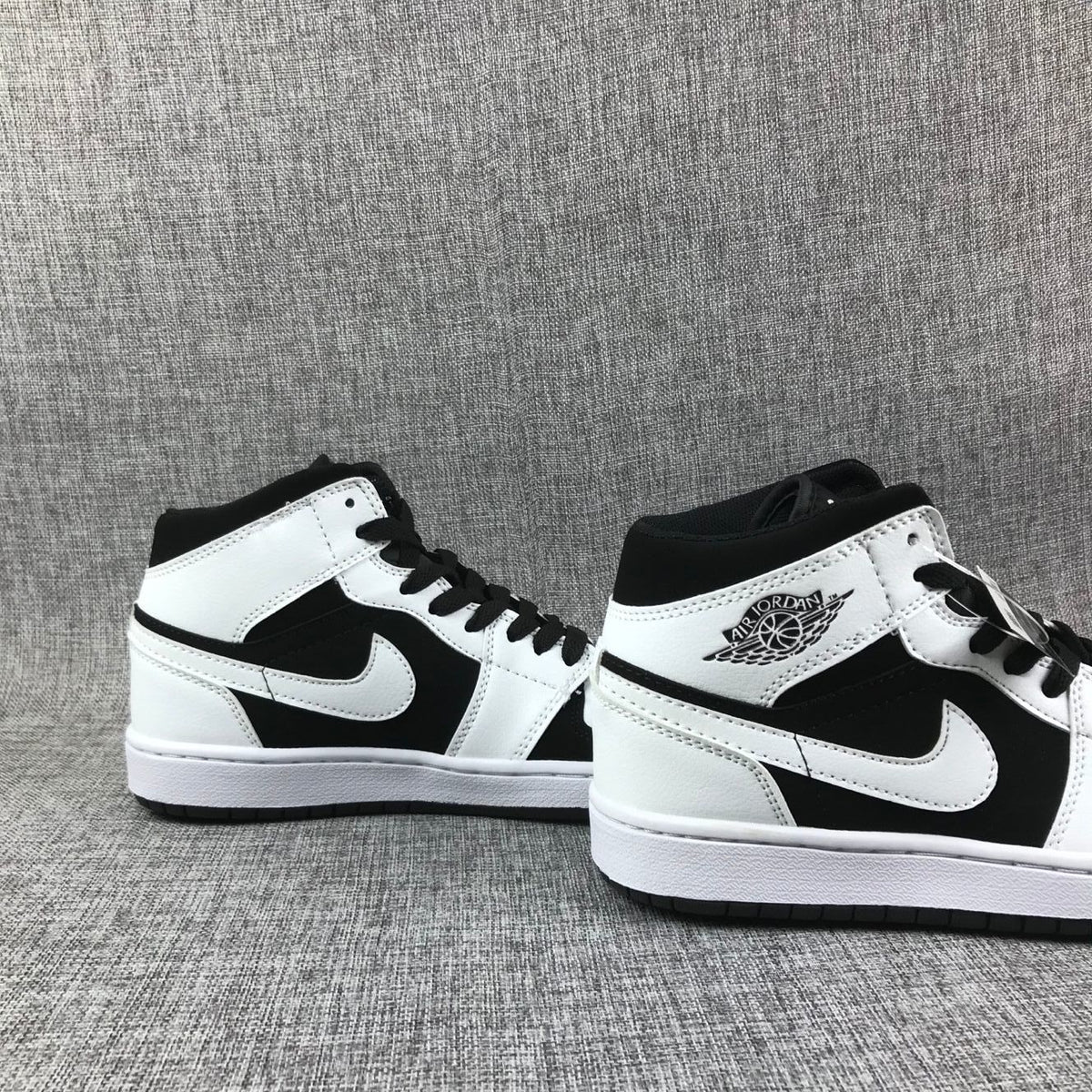 Pair of black-and-white Jordan Air Jordan 1 Mid sneakers shown from angled side views.
