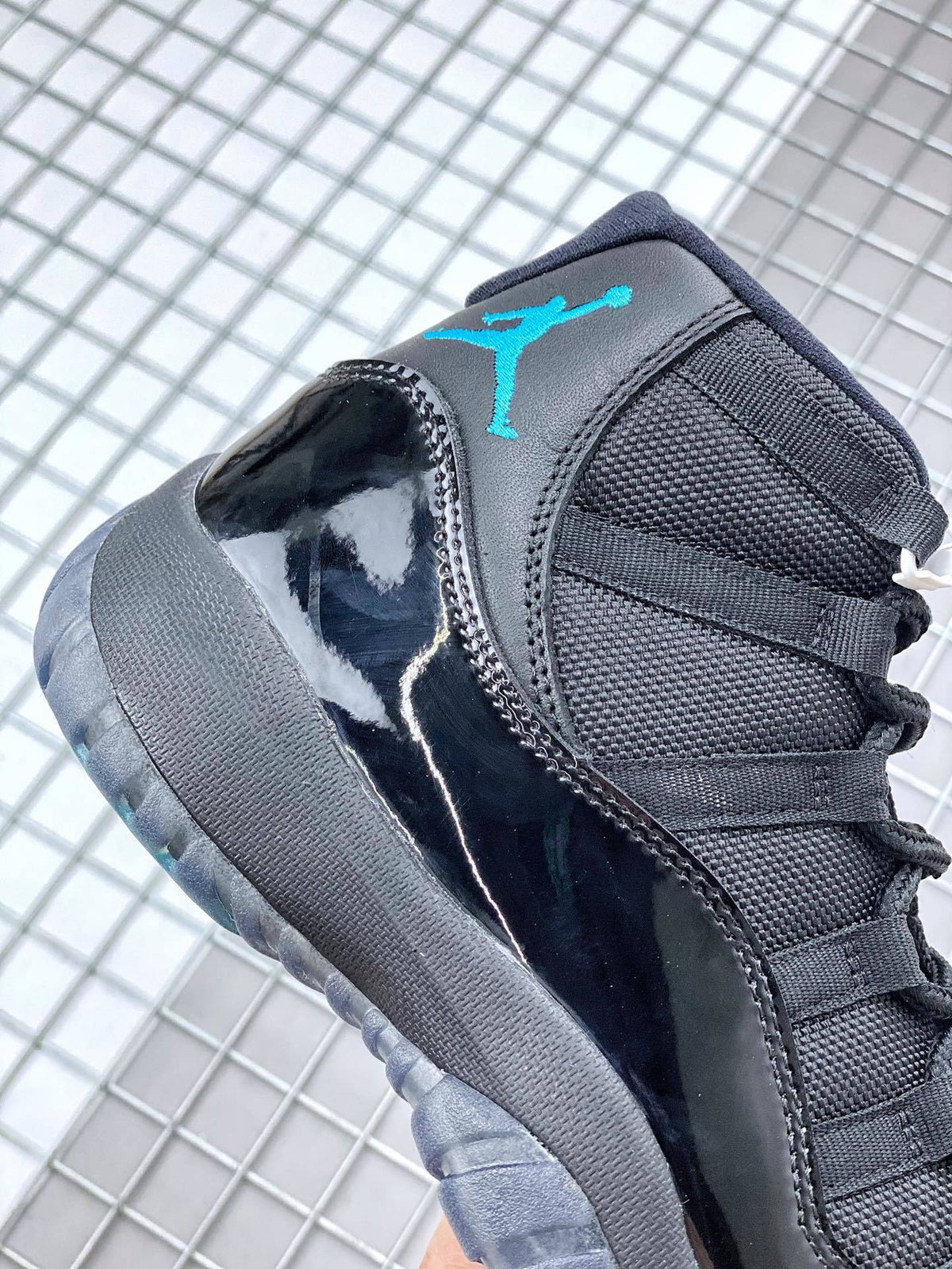 Side close-up showing the black glossy panel, textured upper, blue tongue branding and dark outsole.