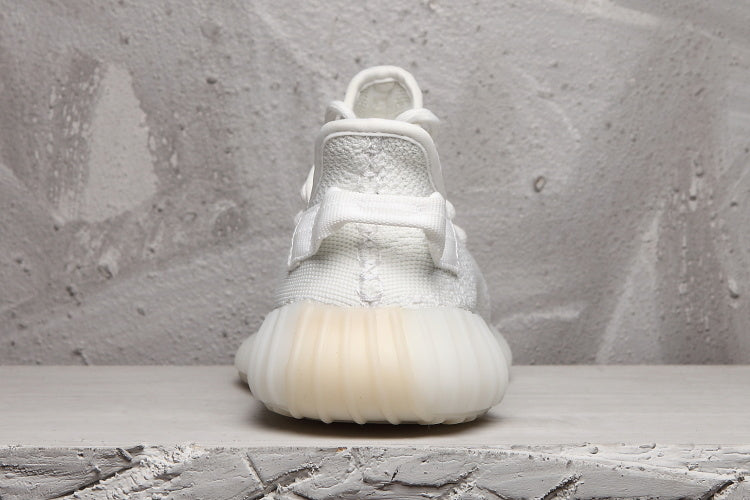 Rear view of a white Yeezy 350 V2 sneaker showing the heel pull tab and ribbed sole.