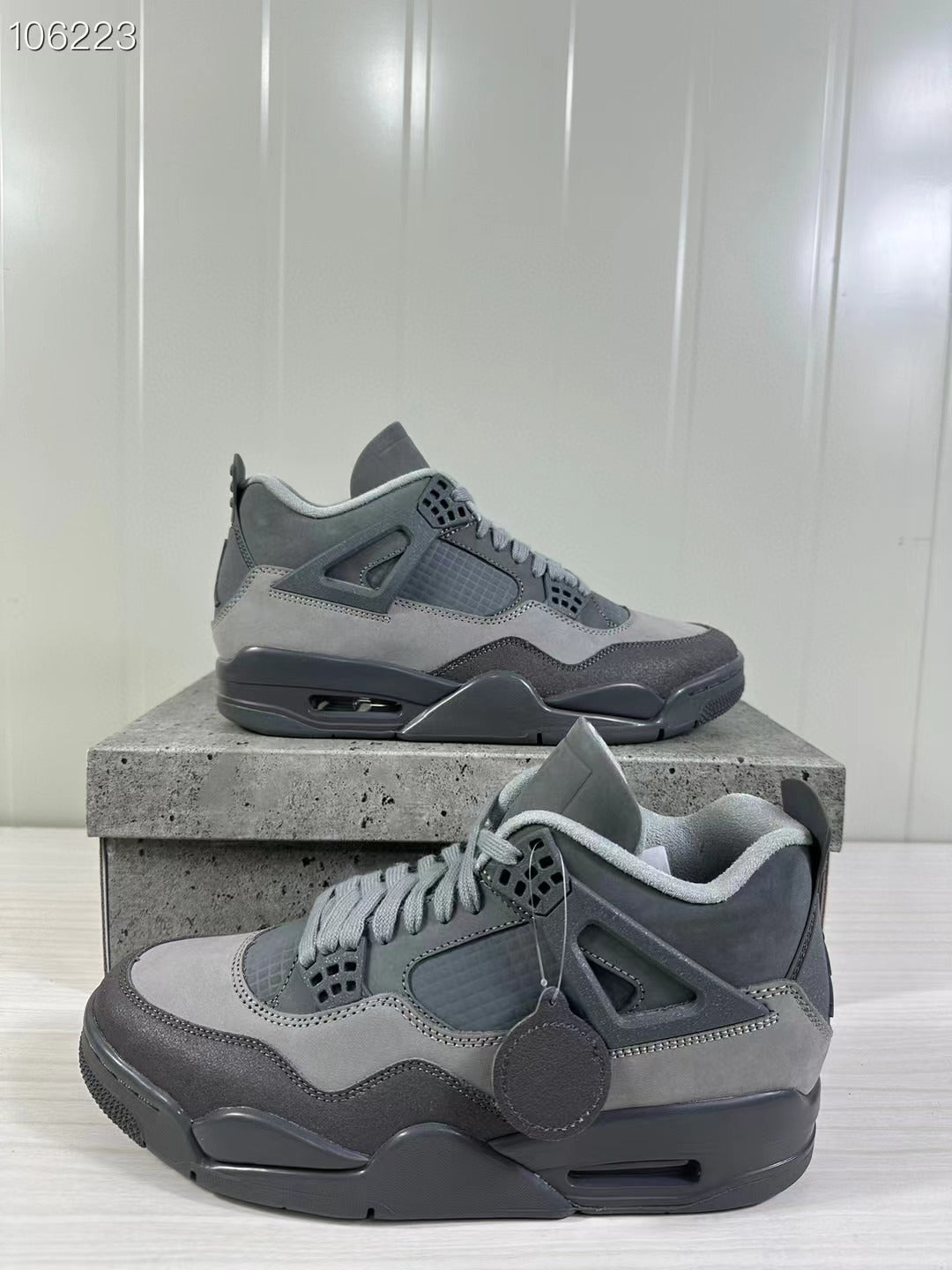 Two grey Air Jordan 4 Retro SE sneakers shown from angled side views on a textured display box.