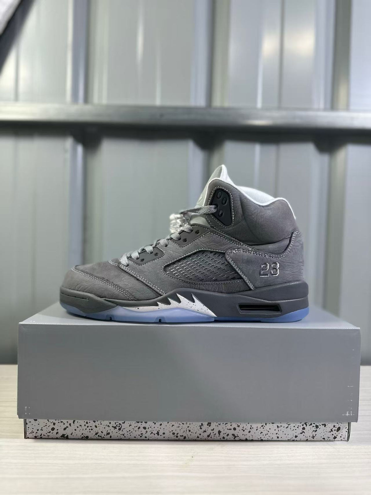 Side profile of a grey high-top sneaker with a ventilated side panel, number 23 detail, black midsole, and translucent outsole.